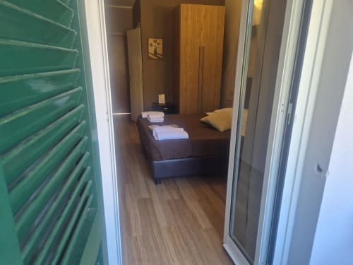 Camera moderna dell'hotel Sestri Levante con pavimento in legno, letto scuro, armadio e persiane verdi visibili