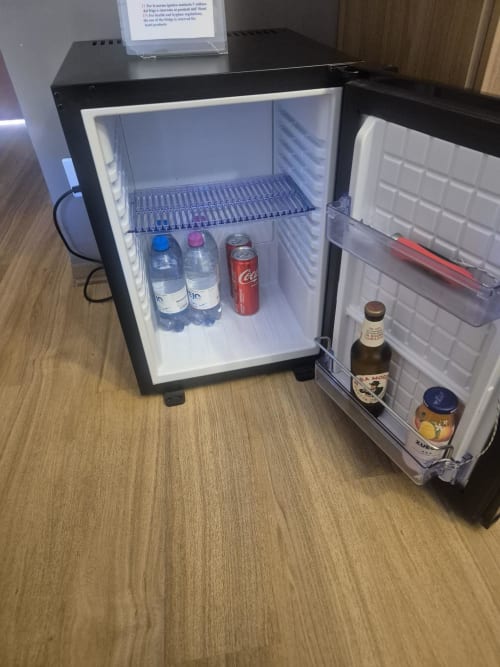 Piccolo frigobar nero fornito di bottiglie d'acqua, cola e birra presso l'hotel Seaside ENNE CI HOLDING SRL a Sestri