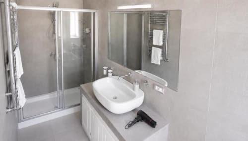 Bagno moderno con lavabo bianco, specchio e box doccia in vetro presso Politeama Central Suite, Palermo