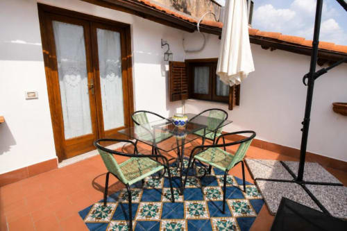 Terrazza con tavolo da pranzo e sedie della Politeama Central Suite a Palermo, con piastrelle decorative e vista sulle montagne.