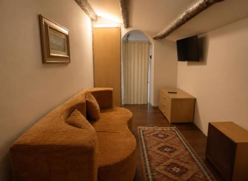 Accogliente zona living della suite Porta Felice al Politeama Central Suite Palermo con divano arancione, TV e arredi tradizionali