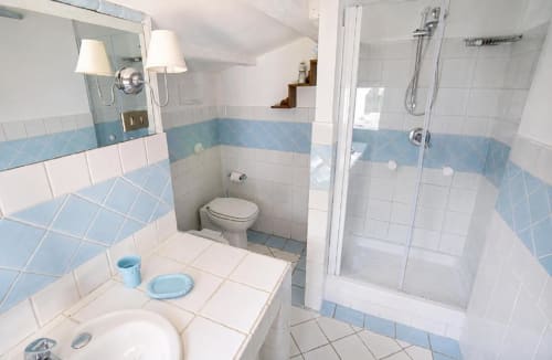 Bagno luminoso con piastrelle blu e bianche, lavabo, WC e cabina doccia in vetro presso la Politeama Central Suite di Palermo
