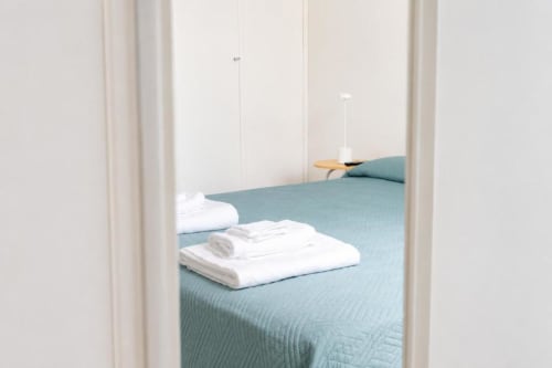 Camera luminosa della Politeama Central Suite a Palermo con coperta teal, asciugamani bianchi e arredamento minimalista
