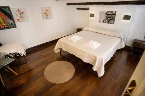 Camera da letto spaziosa nel B&B di Palermo con letto matrimoniale, pavimenti in legno, biancheria bianca e parete galleria d'arte
