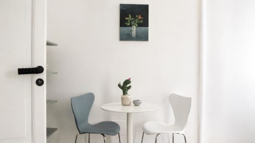 Area salotto moderna nella Politeama Central Suite di Palermo con tavolo bianco rotondo, sedie blu e bianche, cactus in vaso e