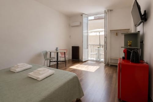 Luminosa suite in Politeama Central Palermo con letto, tavolo da pranzo, balcone con vista su cortile interno e rosso