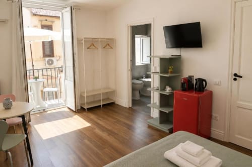 Suite Porta Nuova Politeama Central a Palermo con letto, TV, minibar rosso, armadio, bagno e balcone con corte