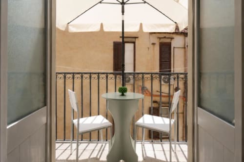 Zona lounge con tavolo e sedie sul balcone della Politeama Central Suite a Palermo, ombrellone con vista sulla corte interna