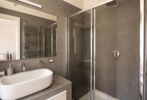 Bagno moderno nella camera Porta Nuova della Politeama Central Suite, Palermo, con lavabo ovale, box doccia e scaldarughe