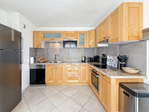 Cuisine moderne avec placards en bois et appareils en acier inoxydable dans un appartement avec vue sur la mer à Calvi