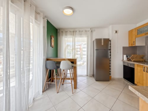 Cuisine moderne et salle à manger avec vue mer dans un appartement de Calvi, bar en bois et équipements en inox