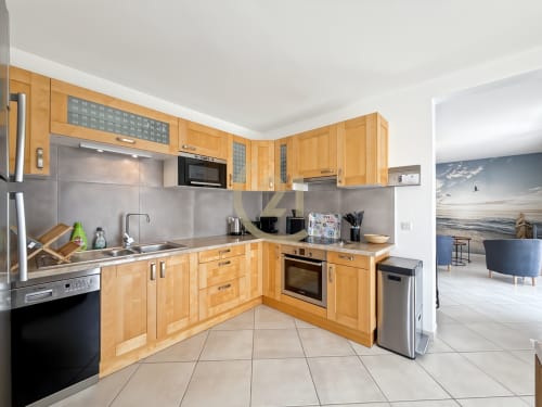 Cuisine contemporaine avec meubles en bois et électroménagers en inox dans un appartement avec vue mer à Calvi