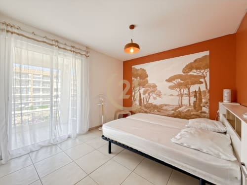 Chambre lumineuse avec mur d'accent orange, œuvres d'art vue mer, literie blanche, accès à la terrasse et équipements modernes à Calvi