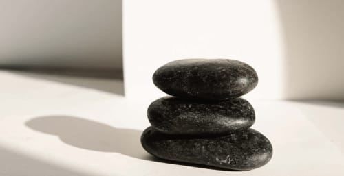 Stacked smooth black spa stones in sunlight at Rio Botteniga Luxury Room & Private SPA, Treviso