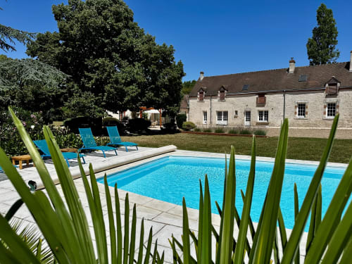 Piscine d'un bleu éclatant avec chaises longues au Domaine De Couilleuse, un manoir en pierre proposant des chambres d'hôtes à Saint Laurent Nouan, France