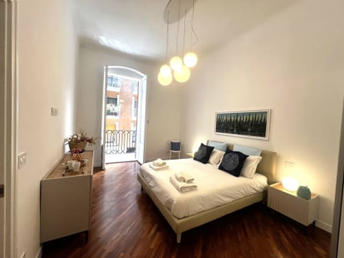 Camera da letto moderna con balcone vista città presso Appartamenti Bari, con lampade a sospensione contemporanee e pavimenti in legno