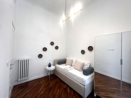 Camera da letto moderna negli Appartamenti Bari con letto bianco, cuscini rigati, quadri decorativi, pavimenti in legno e