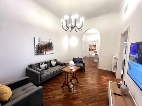 Soggiorno moderno nell'appartamento La casa di Giuni a Bari con divano grigio, tavolo in legno, lampadario e TV
