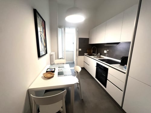 Cucina moderna bianca con rivestimento nero e tavolo da pranzo nell'appartamento La casa di Giuni, Bari