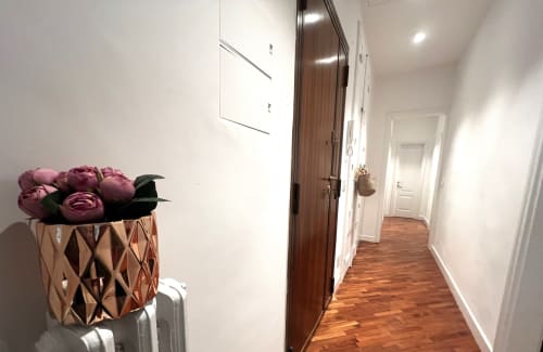 Corridoio dell'appartamento La casa di Giuni a Bari con rose bordeaux, porte in legno scuro e pavimento in legno