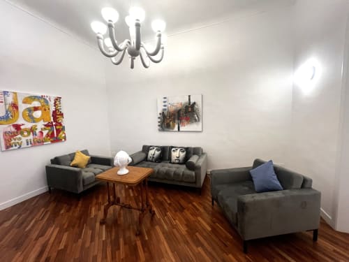 Soggiorno moderno di Appartamenti Bari con divani grigi, tavolo in legno, lampadario e arte contemporanea su pareti bianche