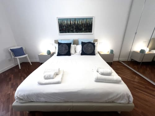 Camera moderna agli Appartamenti Bari con letto bianco, cuscini decorativi scuri e pavimento in legno