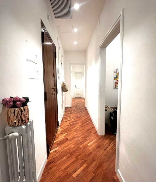 Moderno corridoio degli Appartamenti Bari con pavimenti in legno, pareti bianche e molteplici porte delle camere