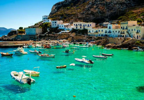 Porto mediterraneo turchese con barche da pesca colorate e edifici imbiancati a Marausa, Sicilia