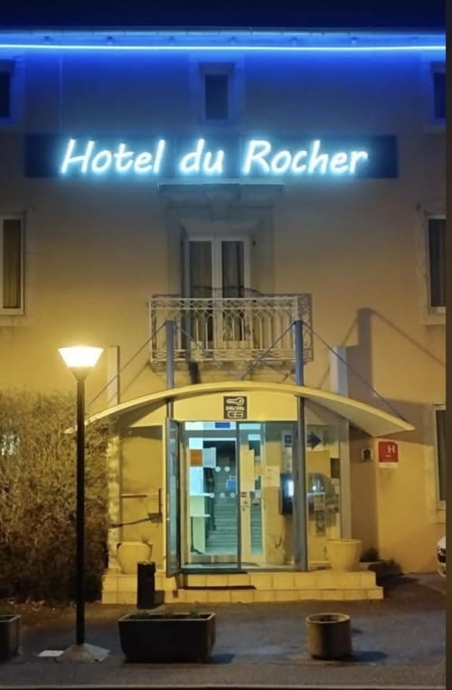 Hôtel du Rocher au Caylar, France - entrée illuminée avec enseigne néon la nuit