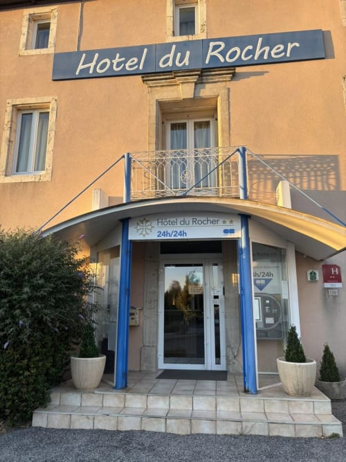 Entrée de l'Hôtel du Rocher au Caylar avec porte encadrée de bleu et signalétique
