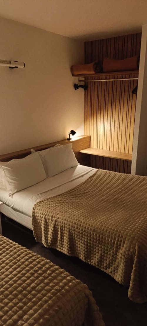 Chambre chaleureuse à l'Hôtel Du Rocher au Caylar avec lit, bureau et rangements intégrés à l'éclairage chaleureux