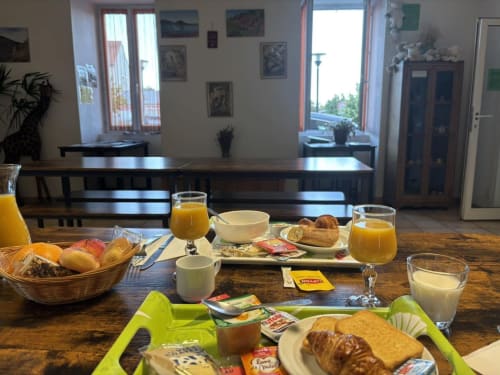 Petit-déjeuner à l'Hôtel Du Rocher au Caylar : croissants, fruits frais, jus et pâtisseries sur table en bois.