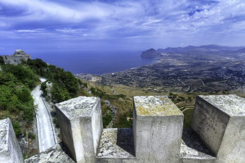 Fortificazioni in pietra dominano la costa di Marausa lido, Trapani, Sicilia, con il blu Mare Mediterraneo e il paesaggio costiero