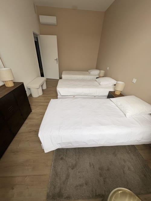Chambre spacieuse du Le Montreal BnB avec trois lits et draps blancs à Montréal du Gers
