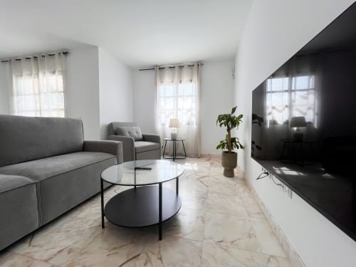 Modern living room at Casa Reguera villa in Geafond with gray sofa, smart TV, and marble flooring