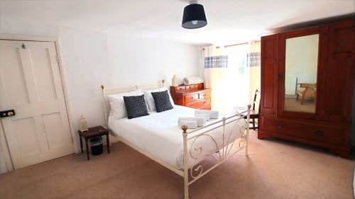 Spacious bedroom at Llwyncadfor holiday home in Llandysul with metal bed frame, wooden wardrobe, and cream carpet