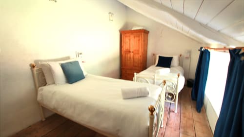 Bright attic bedroom in Llwyncadfor villa with two white beds, wooden wardrobe, and blue curtains in Llandysul