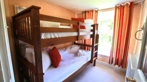 Wooden bunk bed with white linens and red pillow in bright bedroom at Llwyncadfor holiday home, Llandysul