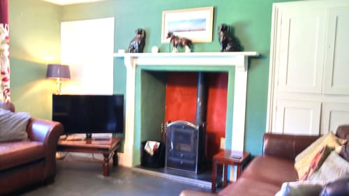 Cozy holiday villa lounge with turquoise walls, fireplace, leather sofas, TV, and modern amenities at Llwyncadfor, Llandysul