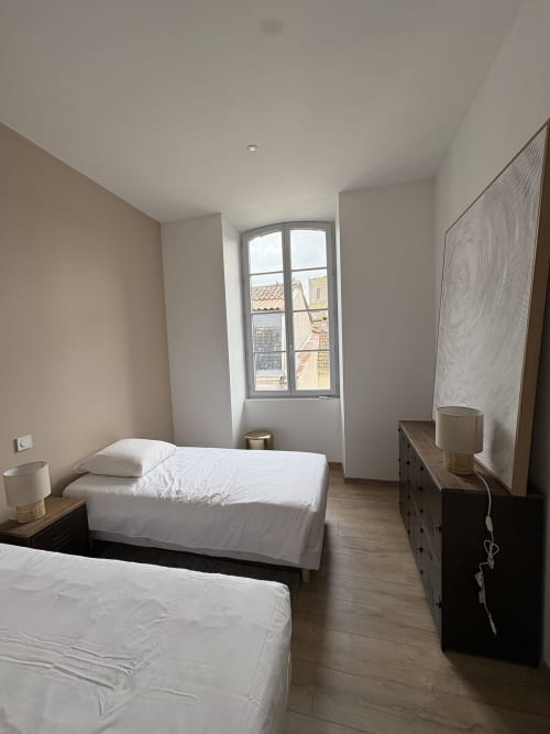 Chambre twin moderne au B&B Le Montreal avec vue sur la ville, lits blancs, parquet et architecture en pierre