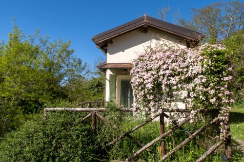 Casa di Cinti's rustic cottage in Loiano with blooming pink flowers and wooden fence
