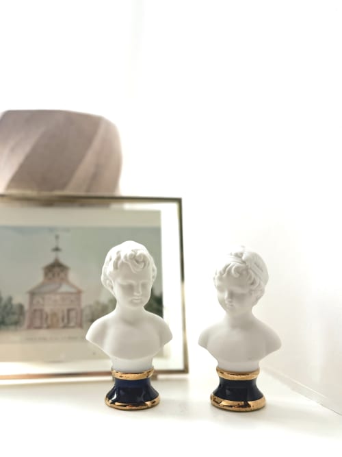Deux bustes en marbre blanc aux socles dorés exposés dans la chambre Elisabeth de la Maison Mansel, Mesnil-en-Ouche, avec des œuvres encadrées