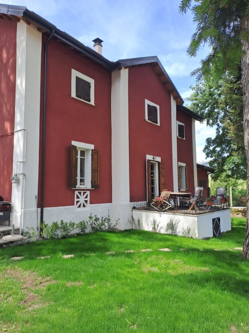 Villa bianca e rossa con portico bianco e prato verde dell'Antico Chalet Momosa a Ovindoli, Italia