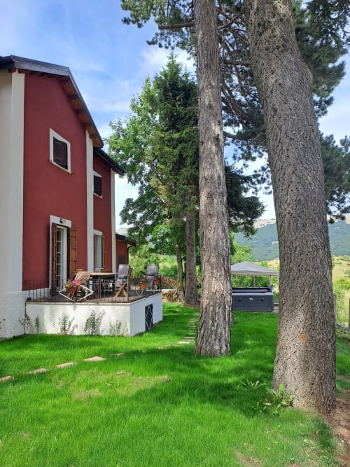Villa chalet rosso e bianco con vista montagna, maestosi pini, prato verde e terrazza presso l'Antico Chalet Momosa a Ovindoli