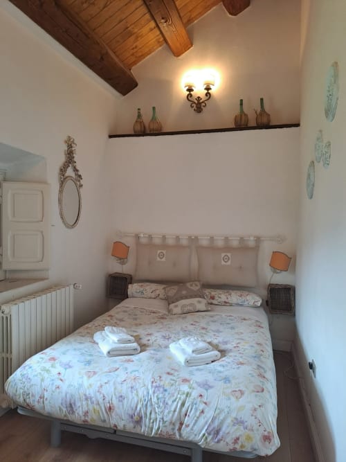 Camera accogliente dell'Antico Chalet Momosa, Ovindoli, con biancheria floreale, travi in legno a vista e arredamento rustico da rifugio di montagna