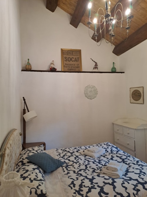 Accogliente camera da letto nell'Antico Chalet Momosa con travi a vista, mensola decorativa e biancheria fantasia