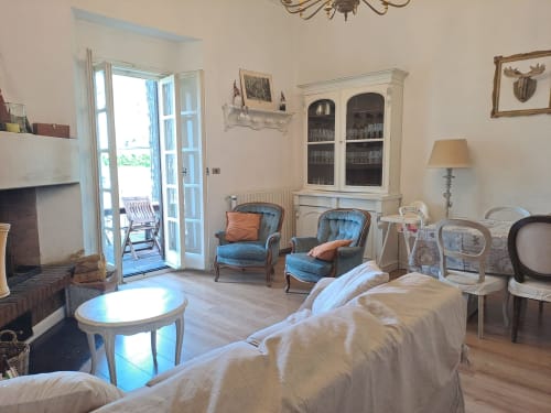 Elegante soggiorno con camino, poltroncine blu e porte-finestre che si aprono sulla vista delle montagne presso l'Antico Chalet Momosa