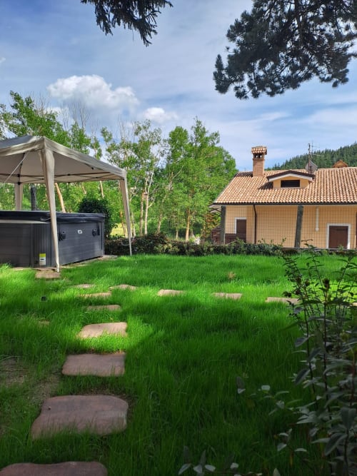 Giardino del Chalet Maxi Mimosa con vialetto in pietra, gazebo e villa in terracotta tra le montagne di Ovindoli