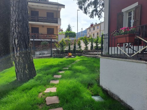 Affascinante passeggiata nel lussureggiante giardino dell'Antico Chalet Momosa a Ovindoli, con lastre di pietra che conducono attraverso il prato verso
