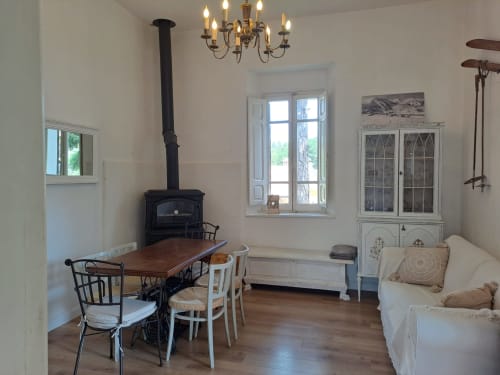 Accogliente soggiorno di villa ad Antico Chalet Momosa con stufa a legna, tavolo da pranzo, arredi bianchi e vista montagna